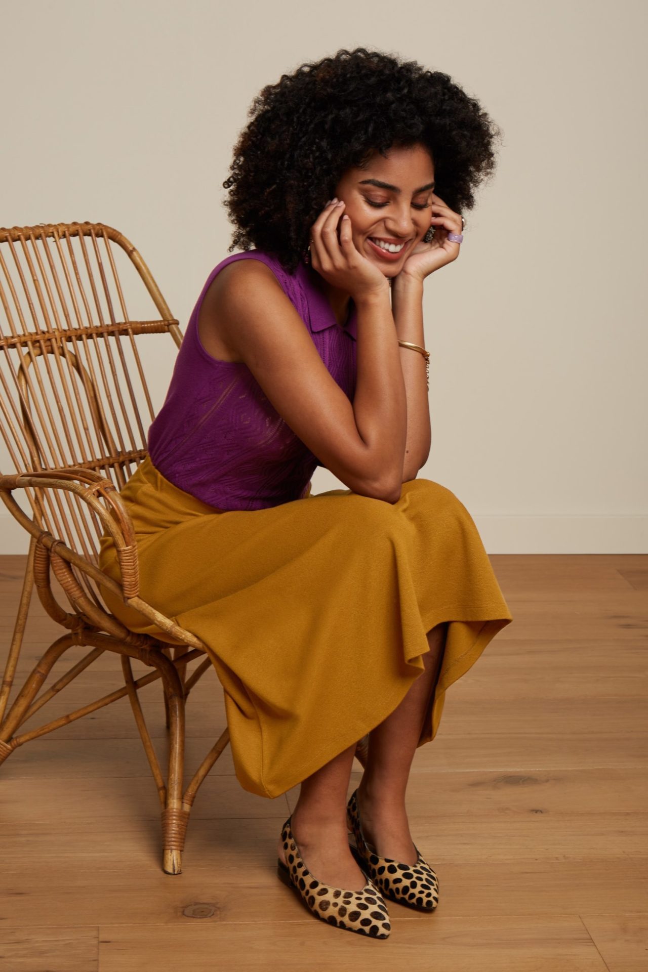 An elevated eCommerce promotional image featuring a delighted woman seated on a chair with a joyful smile, beautifully captured by I Heart Studios.