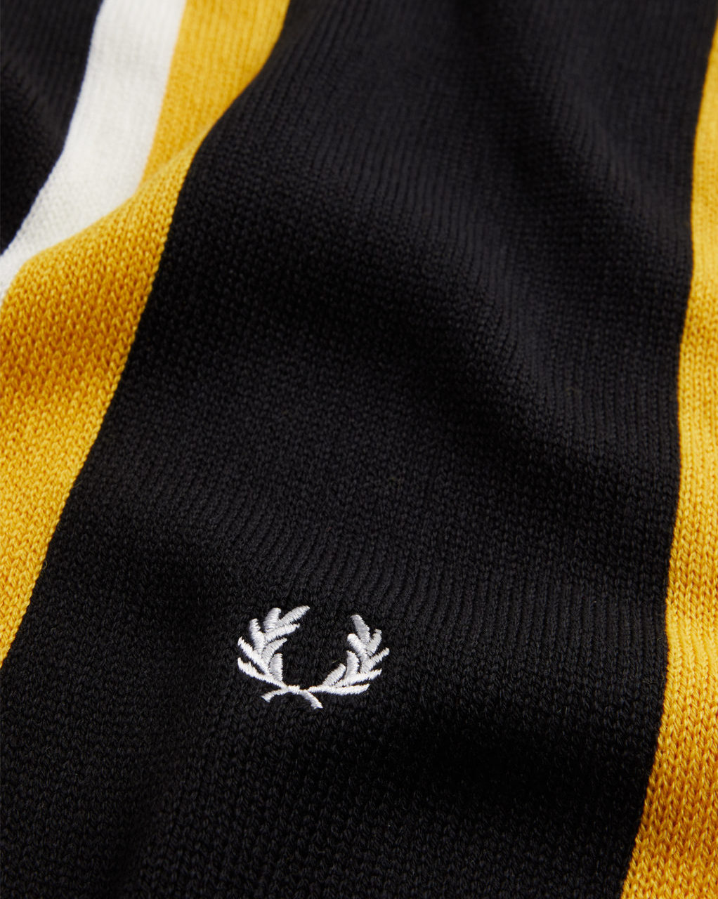 A detailed packshot fashion image showcasing a black and yellow striped scarf from Fred Perry, professionally captured by I Heart Studios.