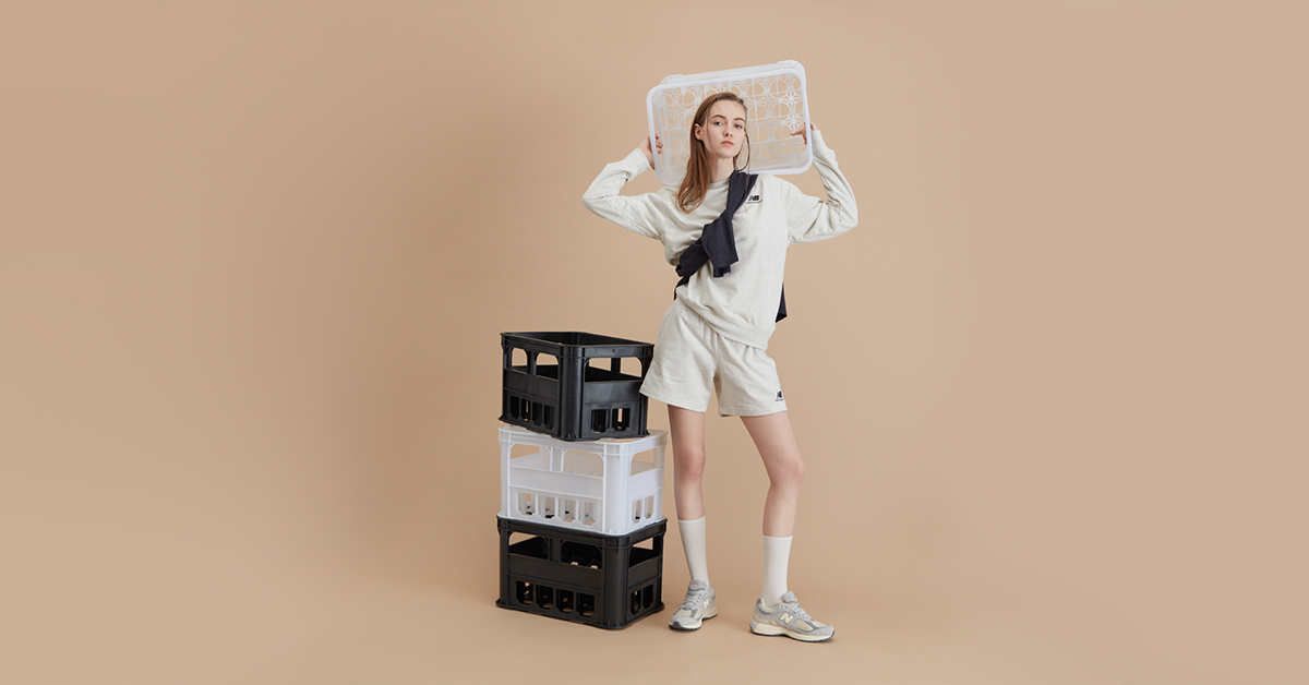 An elevated eCommerce promotional image of a woman holding a milk crate with a sportswear outfit, captured by I Heart Studios.