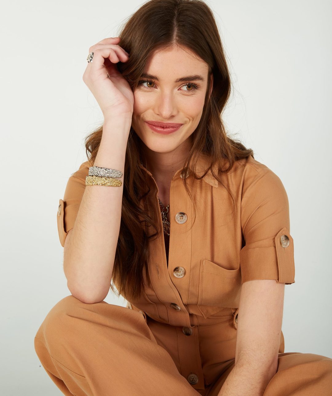 A girl wearing a stylish brown outfit, sitting on the floor with a joyful expression. This fashion body model ecommerce image was captured by I Heart Studios.