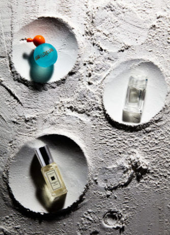 A creative product image of three perfume bottles placed on a moon surface-like background, inspired by the beauty and allure of the moon. Photographed by I Heart Studios.